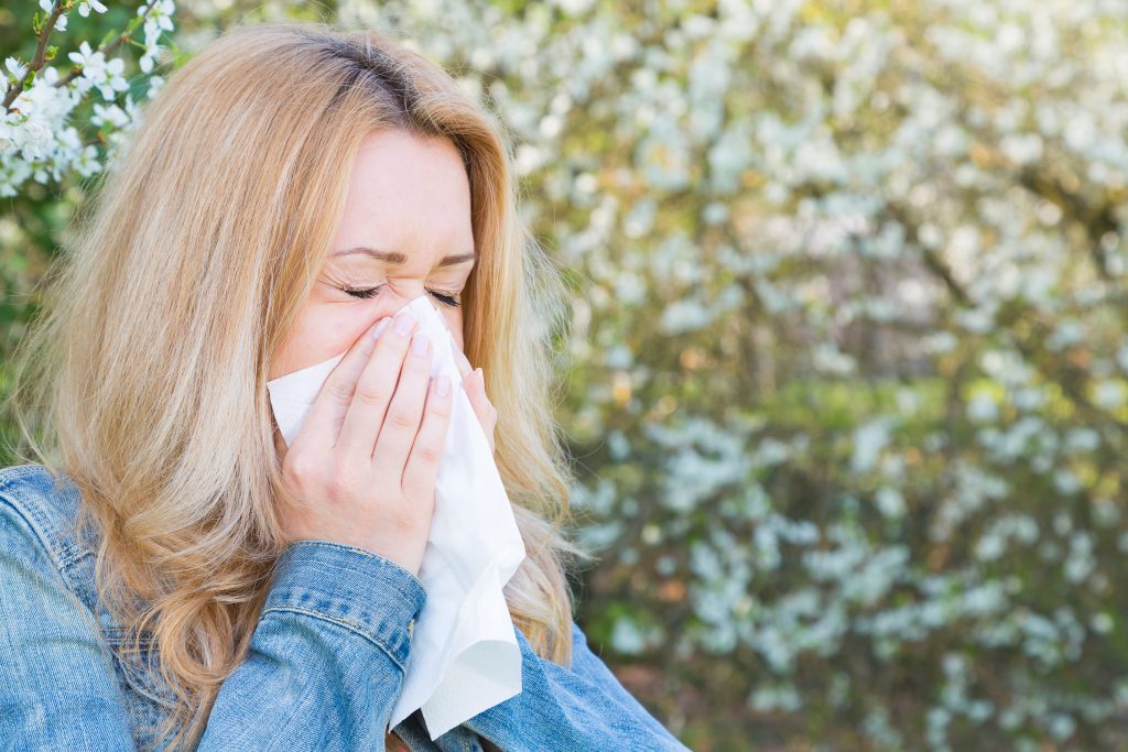 Woman blowing her nose outside